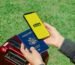 Hands holding a smartphone with eSIM and a passport near a luggage outdoors, ideal for travel concepts.