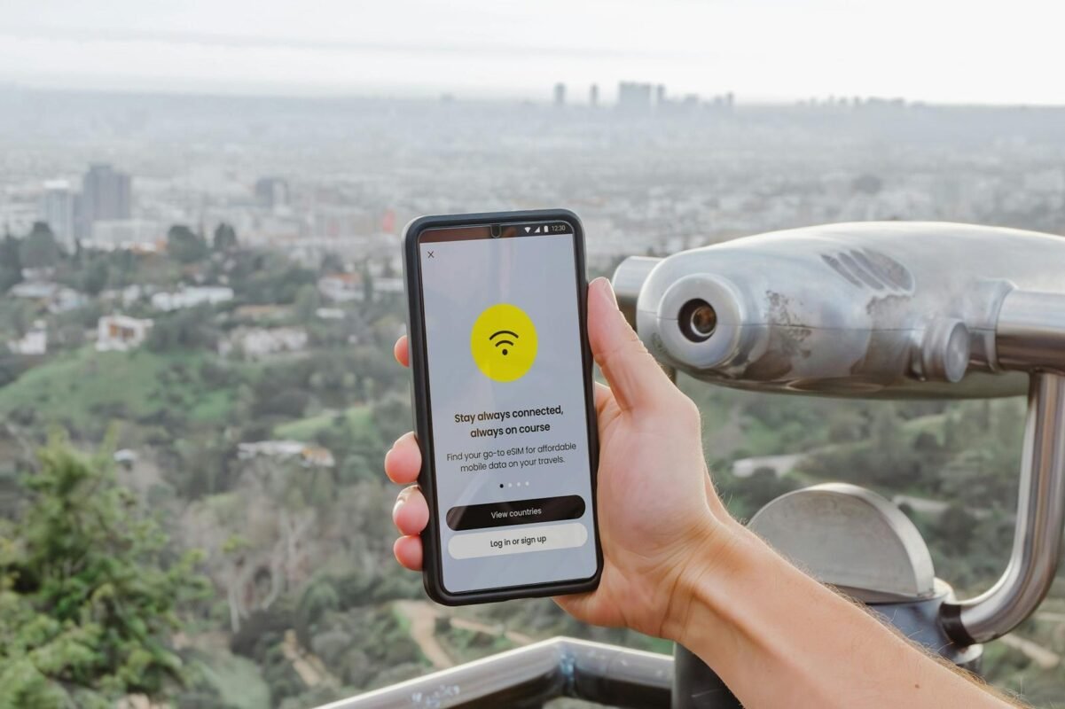 Smartphone displaying connectivity app with Los Angeles cityscape in the background.