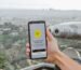 Smartphone displaying connectivity app with Los Angeles cityscape in the background.